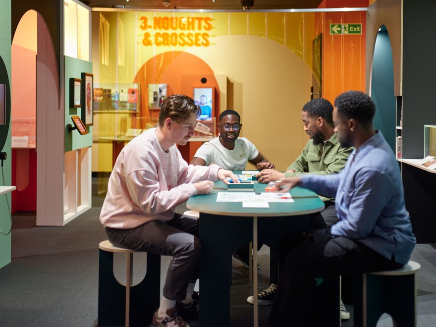four people sit around a table in an exhibition