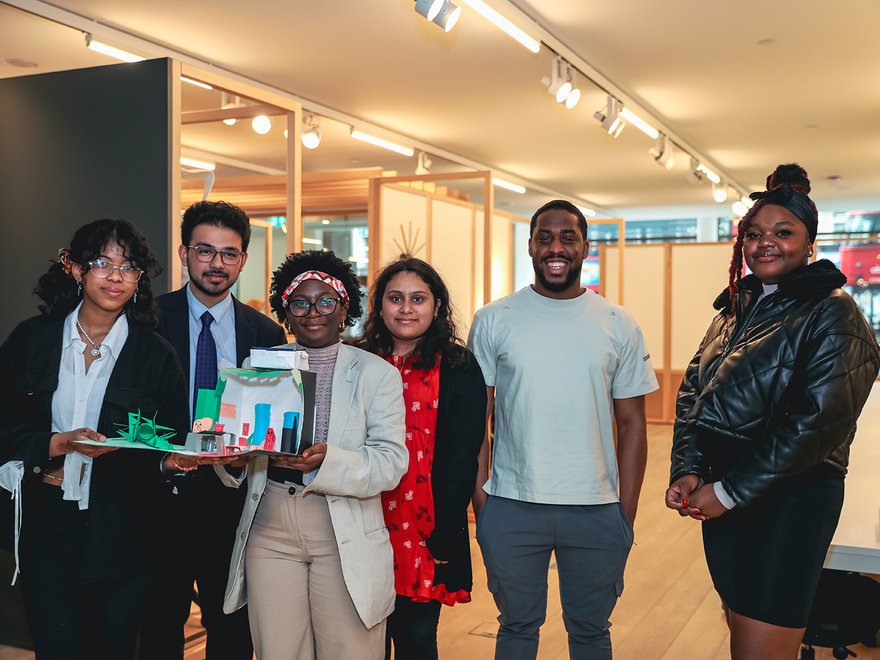 a group of people look at the camera, some are holding up an architectural model