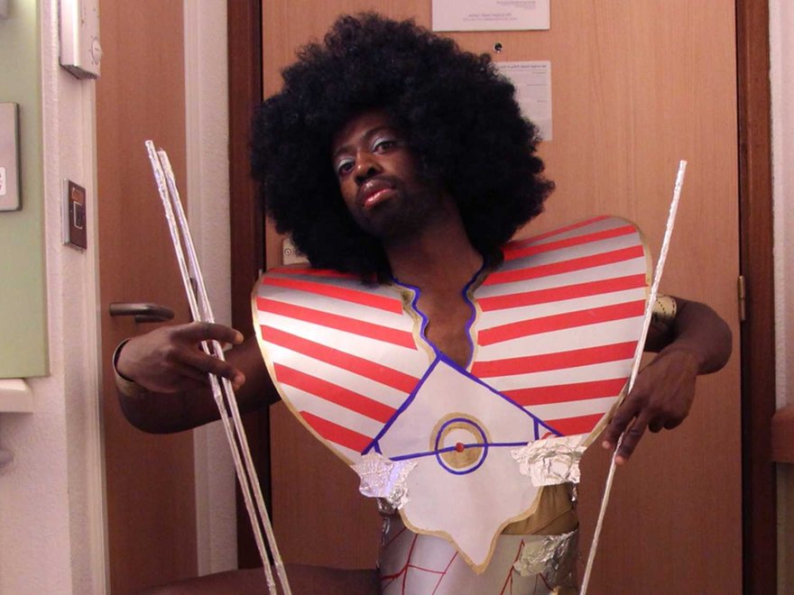 A man sits with a big white afro wig