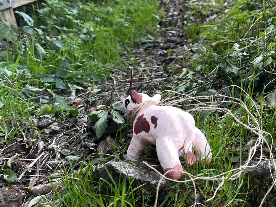 A photograph of a country road with a toy cow