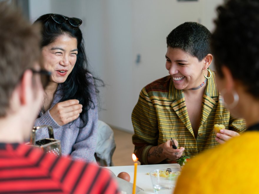 Four people laugh together at a table
