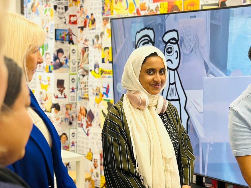 A young woman wearing a headscarf smiles at the camera