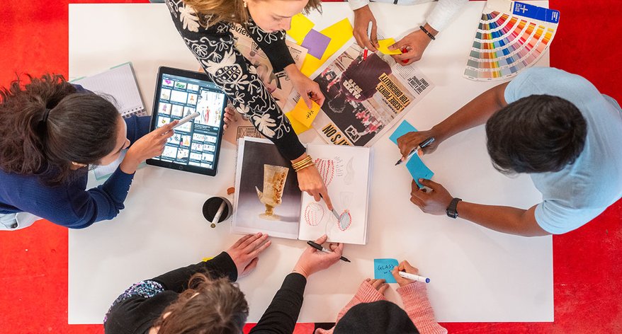 A group of RCA students collaborate on a creative project with pens and post it notes around a table