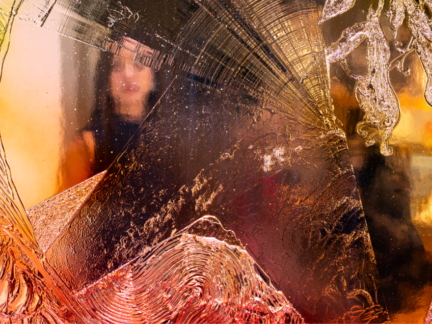 A shimmering feflective artwork with different colours and a woman's reflection